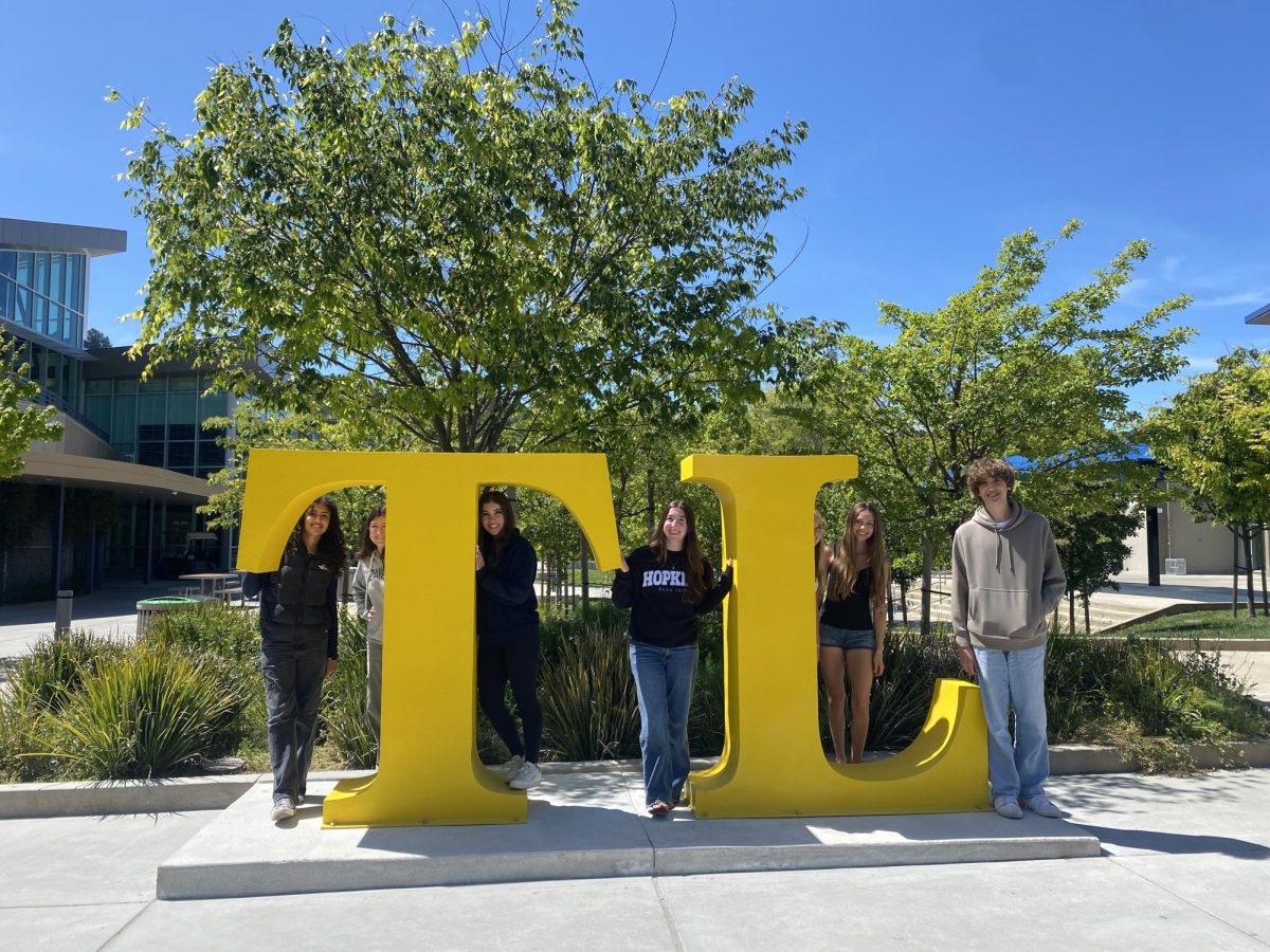 Journalism students pose in front of the new "TL" sign